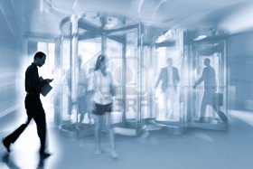 9787643-intentional-motion-blurred-image-of-a-business-group-walking-in-office-lobby-and-through-revolving-d.jpg